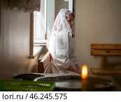 Gomel, Belarus - 02 Sept 2023: Beautiful bride in white robe and veil sitting near window in church. Редакционное фото, фотограф Дмитрий Нечаев / Фотобанк Лори