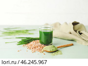 Glass with fresh wheatgrass juice, seeds and powder on color wooden background. Стоковое фото, фотограф Pixel_shot / Фотобанк Лори