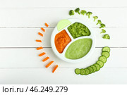 Plate with different healthy baby food on white wooden table. Стоковое фото, фотограф Pixel_shot / Фотобанк Лори
