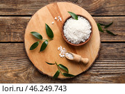 Board with bowl of sea salt and scoop on wooden background. Стоковое фото, фотограф Pixel_shot / Фотобанк Лори