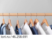 Rack with hanging clothes on light background. Стоковое фото, фотограф Pixel_shot / Фотобанк Лори
