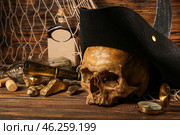 Human skull with pirate hat, golden nuggets, bottle of rum and travel equipment on brown wooden background. Стоковое фото, фотограф Pixel_shot / Фотобанк Лори