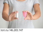 Woman holding tampon and menstrual cup on light background, closeup. Стоковое фото, фотограф Pixel_shot / Фотобанк Лори