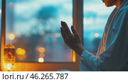Muslim woman praying with open hands in front of window at dusk. Стоковое AI-видео, аниматор Юрий Поздников / Фотобанк Лори