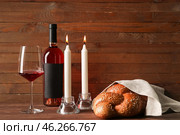 Traditional challah bread with wine and glowing candles on wooden background. Shabbat Shalom. Стоковое фото, фотограф Pixel_shot / Фотобанк Лори
