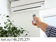 Young man switching on air conditioner at home. Стоковое фото, фотограф Pixel_shot / Фотобанк Лори