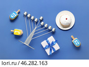 Hannukah composition with menorah, dreidels, gift box and donut on blue background. Стоковое фото, фотограф Pixel_shot / Фотобанк Лори