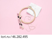 Wooden embroidery hoop with mouline threads, pins and canvas on pink background. Стоковое фото, фотограф Pixel_shot / Фотобанк Лори