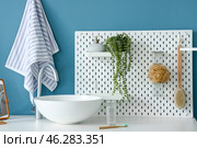Table with sink, glass of water, toothbrush and pegboard near blue wall. Стоковое фото, фотограф Pixel_shot / Фотобанк Лори