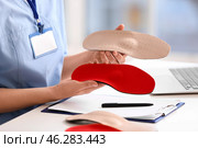 Young female nurse holding different orthopedic insoles in clinic, closeup. Стоковое фото, фотограф Pixel_shot / Фотобанк Лори