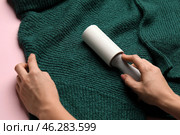 Woman cleaning green sweater with lint roller, closeup. Стоковое фото, фотограф Pixel_shot / Фотобанк Лори