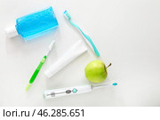 Different tooth brushes with mouth rinse, paste and apple on white background. Стоковое фото, фотограф Pixel_shot / Фотобанк Лори