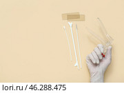 Hand in medical glove, with gynecological speculum and pap smear test tools on beige background. Стоковое фото, фотограф Pixel_shot / Фотобанк Лори