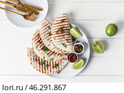 Plate with tasty quesadillas, lime, sauce and pickled jalapenos on light wooden background. Стоковое фото, фотограф Pixel_shot / Фотобанк Лори