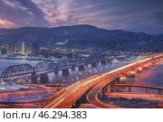Evening panorama of Krasnoyarsk. Nikolaevsky 4th bridge and railway bridge over the Yenisei River at dawn. A Stunning Cityscape at Dusk Featuring Beautiful Twinkling Lights and a Majestic Bridge. Стоковое фото, фотограф Владимир Разгуляев / Фотобанк Лори
