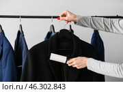 Woman cleaning jacket with lint roller on light background. Стоковое фото, фотограф Pixel_shot / Фотобанк Лори