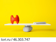 Thyroid gland and cigarettes on teeterboard against yellow background. Concept of balance. Стоковое фото, фотограф Pixel_shot / Фотобанк Лори