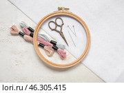 Wooden embroidery hoop with scissors, mouline threads and canvas on grunge white background. Стоковое фото, фотограф Pixel_shot / Фотобанк Лори