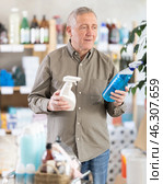 Senior man studies label and choose kitchen cleaner spray. Стоковое фото, фотограф Яков Филимонов / Фотобанк Лори