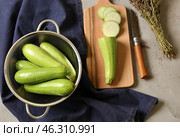 Colander with fresh squashes and cutting board on grey table. Стоковое фото, фотограф Pixel_shot / Фотобанк Лори