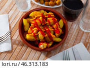 Prepared patatas bravas with sauce served on plate on wooden table. Стоковое фото, фотограф Яков Филимонов / Фотобанк Лори