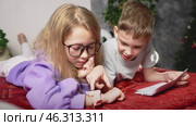 Kids excitedly examine smartwatch, discovering functions together. Boy points to screen while girl navigates menu. Digital curiosity, education, and benefits of smart gadgets in childrens daily life. Стоковое видео, видеограф Енваев Андрей / Фотобанк Лори