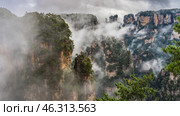 Beautiful mystical landscape. The tall mountain pillars are shrouded in fog. Peaks in the clouds. Green vegetation on the steep slopes of the cliffs. China. Zhangjiajie National Forest Park. Avatar. Стоковое фото, фотограф Вера Ивановна Кубарева / Фотобанк Лори