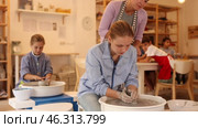 Portrait of a ceramics teacher with students and finished works after a master class. Teenage boy show clay products made themselves in the art studio. Стоковое видео, видеограф Яков Филимонов / Фотобанк Лори