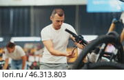 Focused interested sporty young man choosing bike in busy store, examining handlebar system and comparing options. Стоковое видео, видеограф Яков Филимонов / Фотобанк Лори