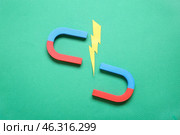 Paper lightning with horseshoe shaped magnet on green background. Стоковое фото, фотограф Pixel_shot / Фотобанк Лори