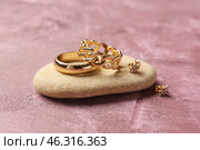 Stone with beautiful rings and earrings on pink background. Стоковое фото, фотограф Pixel_shot / Фотобанк Лори
