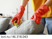 Woman cleaning grey sofa with brush and detergent at home, closeup. Стоковое фото, фотограф Pixel_shot / Фотобанк Лори