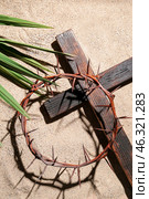Crown of thorns with wooden cross and palm leaf on sand. Good Friday concept. Стоковое фото, фотограф Pixel_shot / Фотобанк Лори