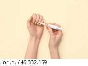 Female hands applying cuticle oil with pen on beige background. Стоковое фото, фотограф Pixel_shot / Фотобанк Лори