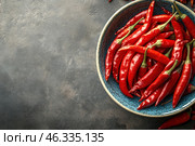 A close-up of a plate filled with fresh red chili peppers. The glossy surface of the peppers reflects the light, highlighting their juiciness and freshness. They are placed in a blue ceramic plate with dark speckles, which creates a contrast with the bright red hue of the vegetables. The background of the image is a dark textured surface, which gives the composition depth and emphasizes the spiciness and richness of the peppers. Стоковое AI-изображение, AI-художник Анна Кривицкая / Фотобанк Лори