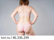 Young woman in pink sexy lingerie, female buttocks and hips with cellulite on gray background. Стоковое фото, фотограф Станислав Тарко / Фотобанк Лори
