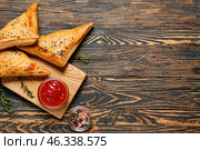 Board with tasty Uzbek samsa and tomato sauce on wooden background. Стоковое фото, фотограф Pixel_shot / Фотобанк Лори