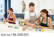 Pupils are sitting near work table, sculpting plate of raw clay under supervision of male teacher. Стоковое фото, фотограф Яков Филимонов / Фотобанк Лори