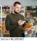 Man purchaser scanning QR code or barcode of bottle grapefruit in supermarket. Стоковое фото, фотограф Яков Филимонов / Фотобанк Лори