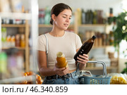 Girl hold packages bottles and choose consider juice in store. Стоковое фото, фотограф Яков Филимонов / Фотобанк Лори