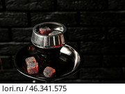 Burning coal for hookah on black brick background. Стоковое фото, фотограф Pixel_shot / Фотобанк Лори