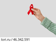 Female hand with red ribbon on white background. World AIDS Day concept. Стоковое фото, фотограф Pixel_shot / Фотобанк Лори