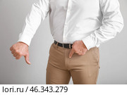 Mature man with urologic disease showing thumb-down on light background. Стоковое фото, фотограф Pixel_shot / Фотобанк Лори