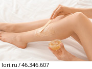 Young woman epilating her leg with liquid sugar on bed, closeup. Стоковое фото, фотограф Pixel_shot / Фотобанк Лори