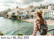 A girl traveler with a backpack on the background of the southern coast of the sea. A woman travels, enjoys life and the environment. Tourism. Стоковое AI-изображение, AI-художник Photojuli / Фотобанк Лори