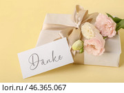 Gift box, card with text DANKE and eustoma flowers on color background, closeup. Стоковое фото, фотограф Pixel_shot / Фотобанк Лори