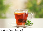 Tea bag dipped in cup with hot beverage on table. Стоковое фото, фотограф Pixel_shot / Фотобанк Лори