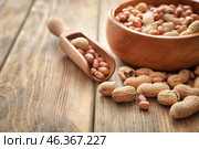 Bowl and scoop with tasty peanuts on wooden table. Стоковое фото, фотограф Pixel_shot / Фотобанк Лори