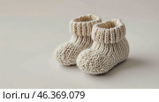 Close up of textile baby booties. Pregnancy concept, Pairs of baby shoes on a blue background. Gender neutral baby garment and accessories. Organic newborn bootie, fashion, branding. Gender neutral. Стоковое AI-видео, аниматор Марина Демидюк / Фотобанк Лори