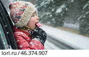 Happy Boy tasting snow through car window during snowfall. Child on a road trip. Little toddler is looking out from auto, opened his mouth, pulled out his tongue, catches snowflakes. Winter fun games. Стоковое AI-видео, аниматор Марина Демидюк / Фотобанк Лори